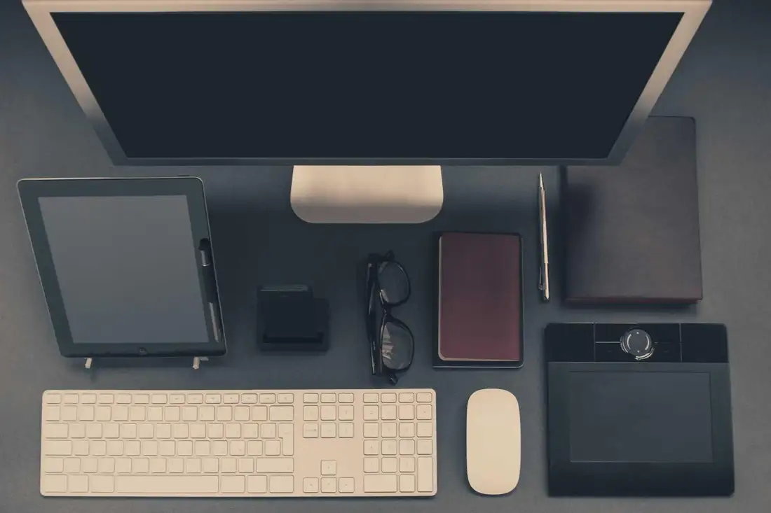 A designer's desk with a laptop, notebook and phone